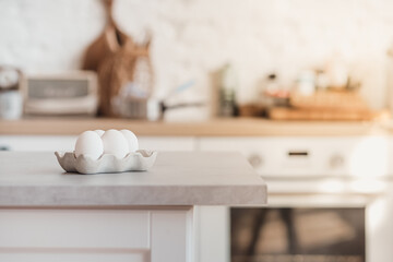 White eggs in a stand are on a gray concrete table in the kitchen. Cooking, food, ingredients.