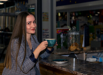 Beautiful, a girl in a cafe drinks coffee, makes notes in a notebook. The concept of happiness.