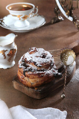 Puff pastry bun with cream cheese and currant.Fresh baked goods. Vertical photo. White porcelain tableware. Powdered sugar.