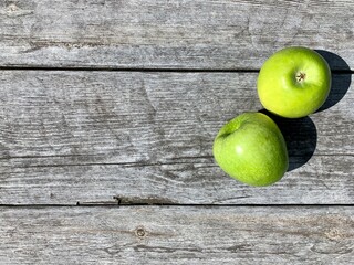 Fashionable food concept. Two green apples on a gray wooden background. Copy space. View from above. Place for your text.
