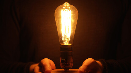 Man is holding an Edison light bulb. - obrazy, fototapety, plakaty
