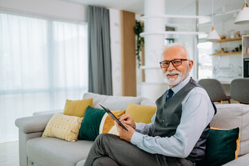 Senior man with glasses on enjoying sitting on the sofa.