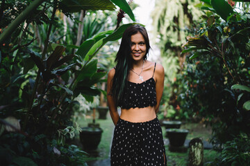Cheerful young lady standing in green garden