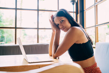 Obraz premium Tired young ethnic employee using laptop in creative workspace