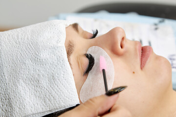 Obraz na płótnie Canvas The procedure for creating a look after the end of the eyelash extension process using a brush.