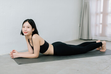 Young asian woman doing sport exercises indoor at home