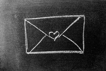 White color chalk drawing in mail envelope with heart shape on blackboard or chalkboard background
