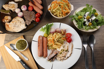 Mix meet chicken beef steak sausage tomato onion garlic fry grill metal pan colorful pasta green salad cheese olive mint basil pesto sauce board knife fork spoon sliced served plate wooden table