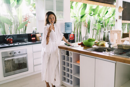 Smiling Asian Woman Cooking In Kitchen