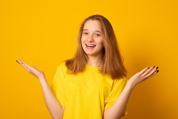 Emotional cute teenage girl on a yellow background. Beautiful positive girl.
