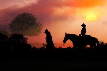 Obraz na płótnie Canvas The silhouette of the cowboy and the setting sun