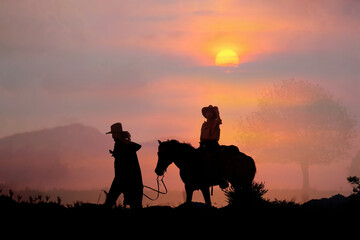 Obraz na płótnie Canvas The silhouette of the cowboy and the setting sun
