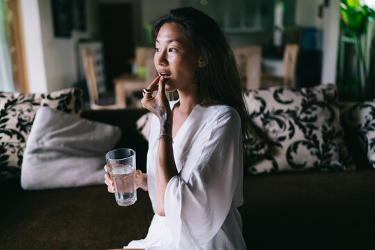 Young Woman Taking Meds On Couch At Home