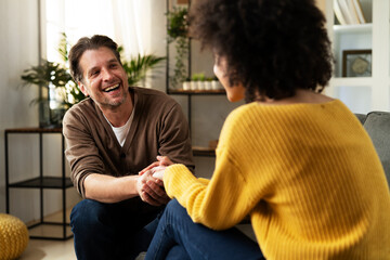 Young couple sitting and talking at home. Woman and man flirting and laughing.
