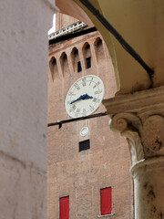 Ferrara, Italy. The clock tower of the Este castle seen from the alley next to the municipal...