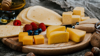 Cheese dish with organic cheeses, fruits, nuts on a wooden background. Delicious cheese snack