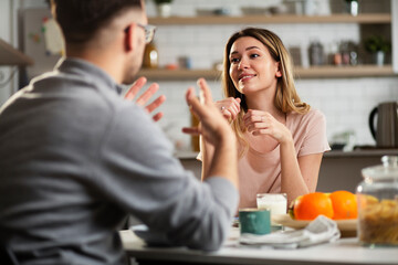 Beautiful young girl enjoying in breakfast with her boyfriend. Loving couple drinking coffee in the kitchen..