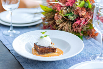 Chocolate cake with a ball of white ice cream is served on a large white plate
