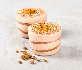 Vegan tiramisu, chocolate nut dried fruit cream dessert in a glass jar on a light gray background