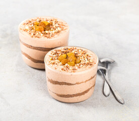 Vegan tiramisu, creamy chocolate walnut raisin dessert in a glass jar on a light gray background
