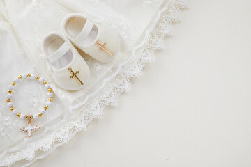Christening background with baptism baby dress, shoes, and cross on pastel background - obrazy, fototapety, plakaty