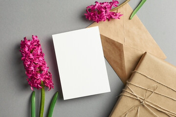 Invitation or greeting card mockup with hyacinth flowers, envelope and gift box on grey