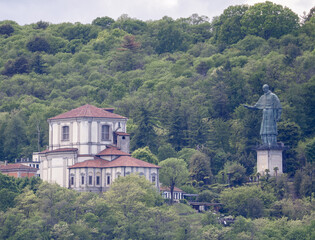Statue of San Carlo Borromeo, patron saint of Arona, stands out in the woods that frame Lake...