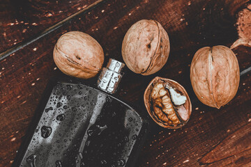 Men's fragrance for strong-minded men in a black bottle on a vintage wooden board with nuts