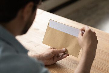 Close up businessman opening envelope with letter, working with correspondence, paperwork, sitting...