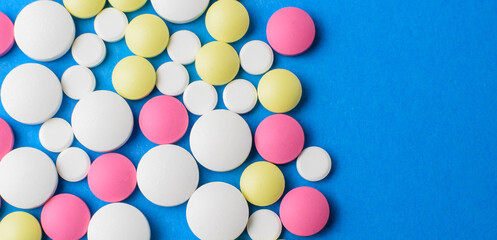 Colored pills on a blue background. The concept of medicine and protection from coronavirus. View from above. Selective focus.