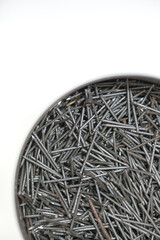heap of finishing nails in a metal tin, on white, photographed with a macro lens, shallow depth of field
