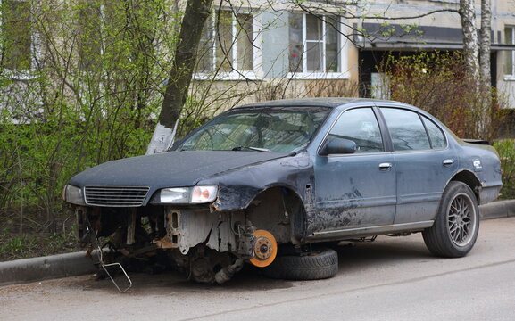 Old rusty dark blue passenger car without wheels in the courtyard of a residential building, Ulitsa Podvoyskogo, Saint Petersburg, Russia, May, 2021
