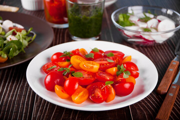 salad of fresh cherry tomatoes with basil on the dinner table