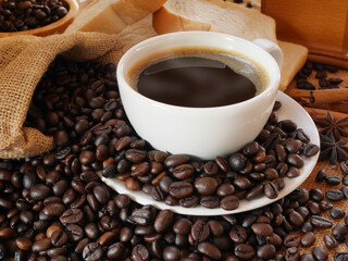 Fototapeta premium A white cup of hot aroma coffee and a sack of coffee beans with some breads for drink and eat in the morning