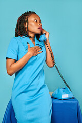 upset surprised excited african american woman secretary calls on the phone. blue background