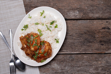 Crispy fried eggs and steamed rice in a white plate on the wooden floor.
