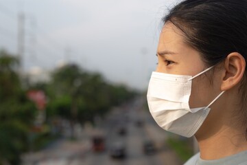 A woman wearing a surgical mask is standing on a flyover.