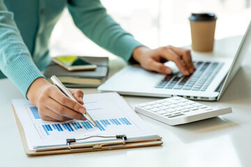 Close up Business woman using calculator and laptop for do math finance on wooden desk, tax, accounting, statistics and analytical research concept	