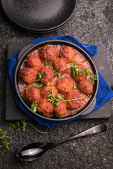 Meat balls with tomato sauce  in a frying pan on a black background.