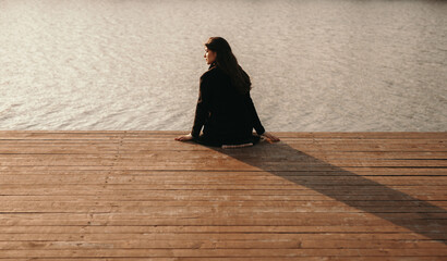 Lonely woman sitting on pier near river