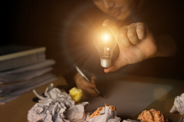 Hand of male holding a light bulb and writing in office. for new idea 
, Inspiration and creative concept. Innovation and development of ideas for corporate success for business. 