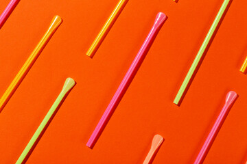 Colored tubules for juice and cocktails on orange background. Cocktail parties. Space for text.