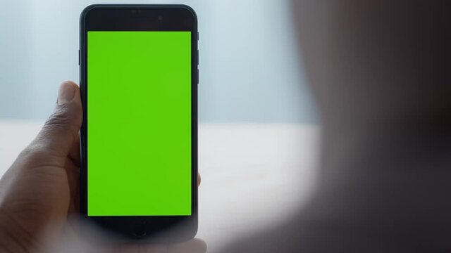 Modern smartphone with green chroma key screen in black male hands, unrecognizable man watching social media