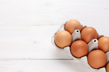 Fresh organic chicken eggs in carton pack or egg container  on white wood background.