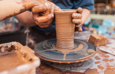 Male potter works at a table with clay doing ceramics