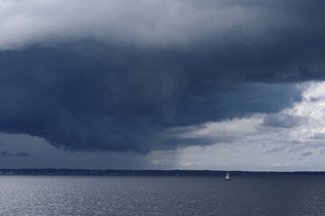 Fototapeta na wymiar Boat Sailing in Center of Storm Formation. Dramatic Background. Danger in Sea Concept.