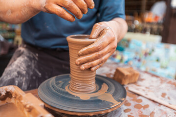 Male potter works at a table with clay doing ceramics