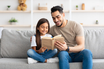 Fototapeta premium Father and daughter reading book spending time together at home