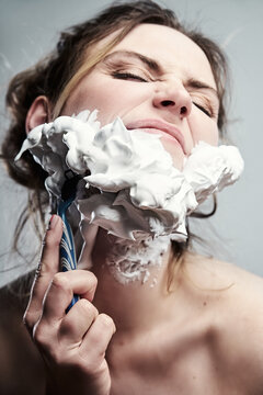 Shaving the beard. Funny female portrait with foam over face