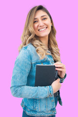 A young girl poses on a pink background holding a diary